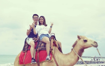 Two people riding a camel on a beach in Bali